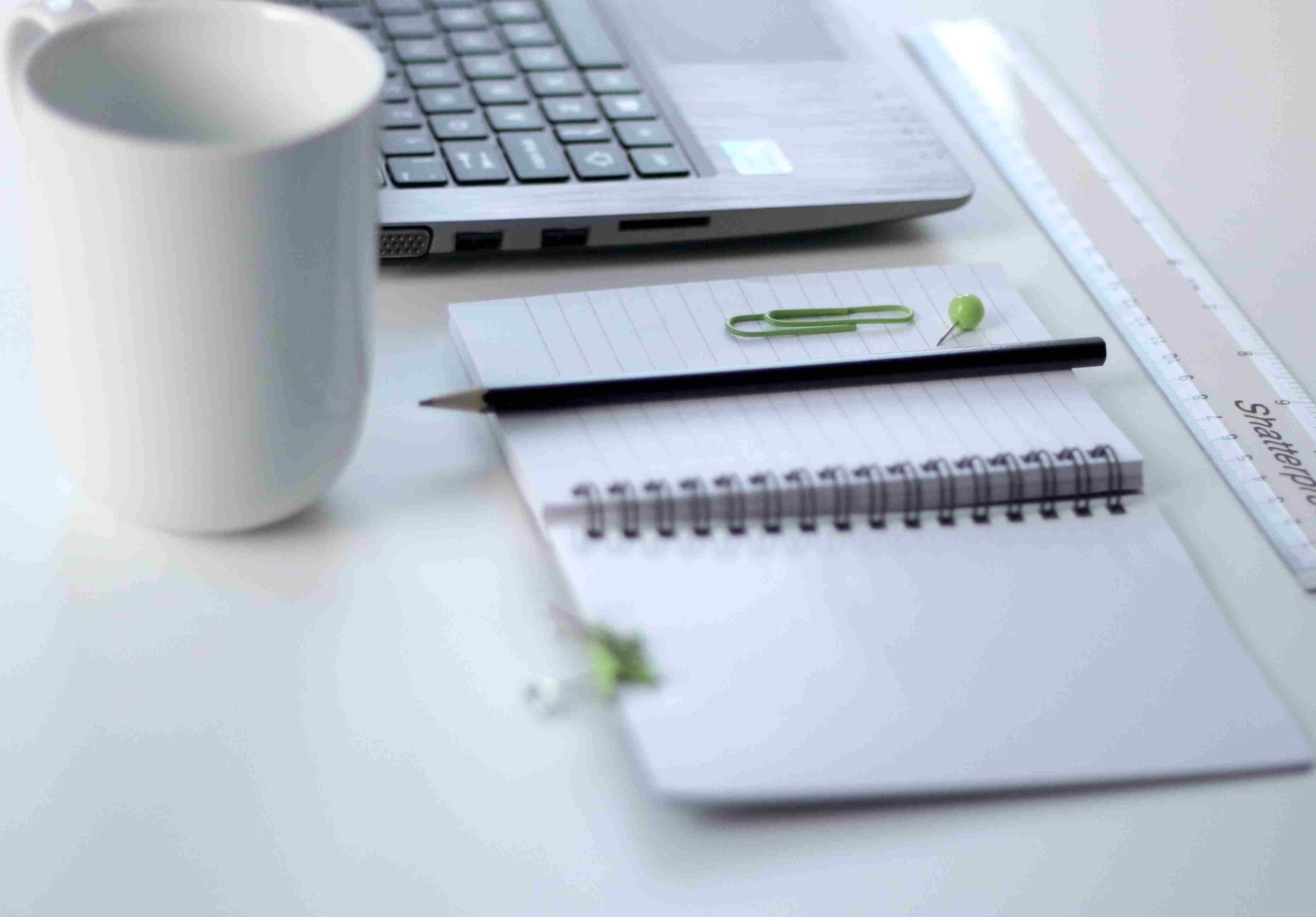 Un quaderno, matita compute, caffè e qualche graffetta verde sulla pagina