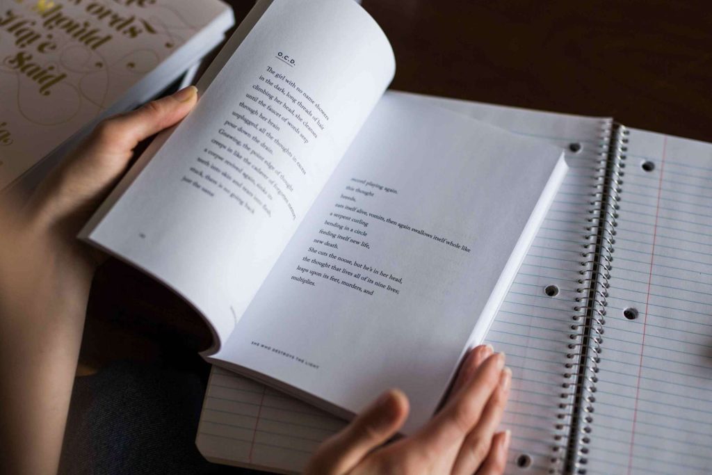 Diventare traduttrice online: Mani di donna che sfogliano libri con accanto un quaderno per appunti