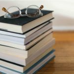 Leggere libri gratis: pila di libri con occhiali retro su tavolo di legno
