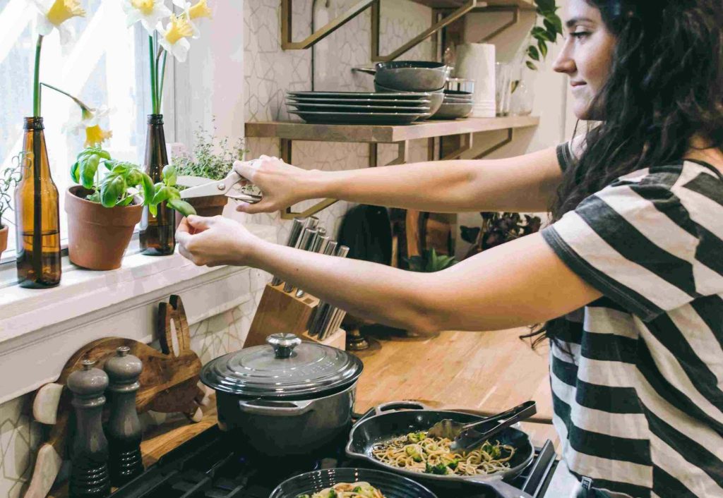Giovane donna che prepara i pasti nella sua bella cucina: questo è un buon modo per risparmiare se hai un reddito basso