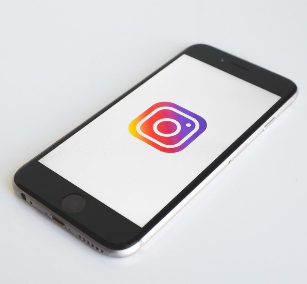 Smartphone nero appoggiato su una scrivania bianca con il logo di Instagram per trovare i tuoi primi clienti gratis