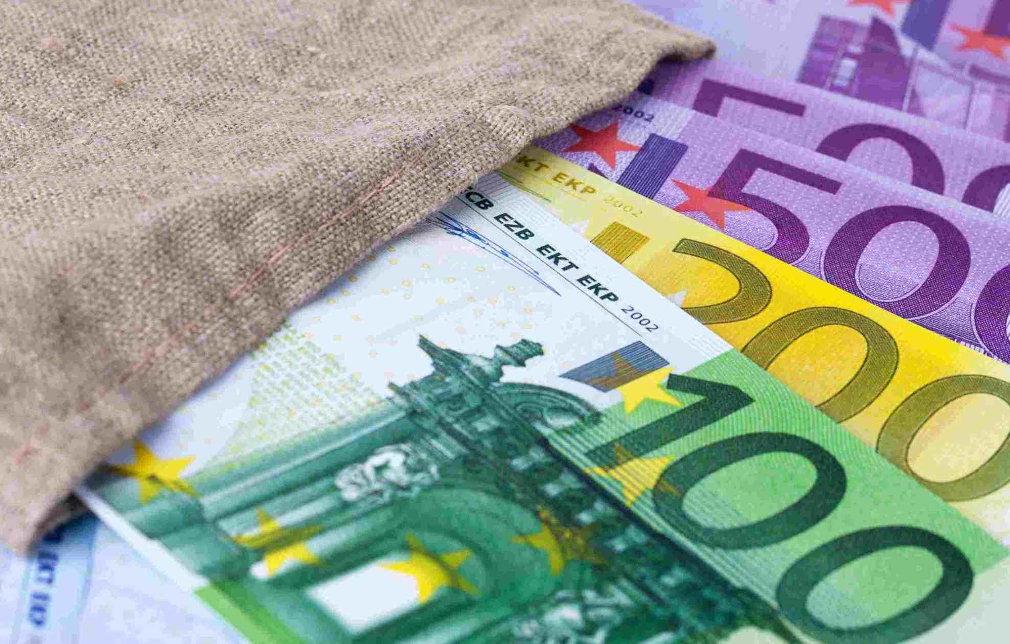 Dettaglio di banconote da 100, 200 e 500 euro appoggiate su una superficie neutra. com'è il tuo approccio al denaro?