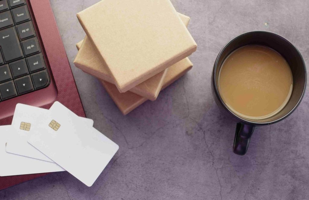 Portatile aperto, carte di credito e una tazza di caffè al latte su un piano di marmo grigio: ecco come risparmiare velocemente diventa difficile