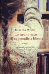 Copertina del libro "Lo strano caso dell'apprendista libraia" con l'immagine di una giovane donna di spalle in abito chiaro a fiorellini e con una lunga treccia castano chiaro, mentre sistema i libri in una libreria.